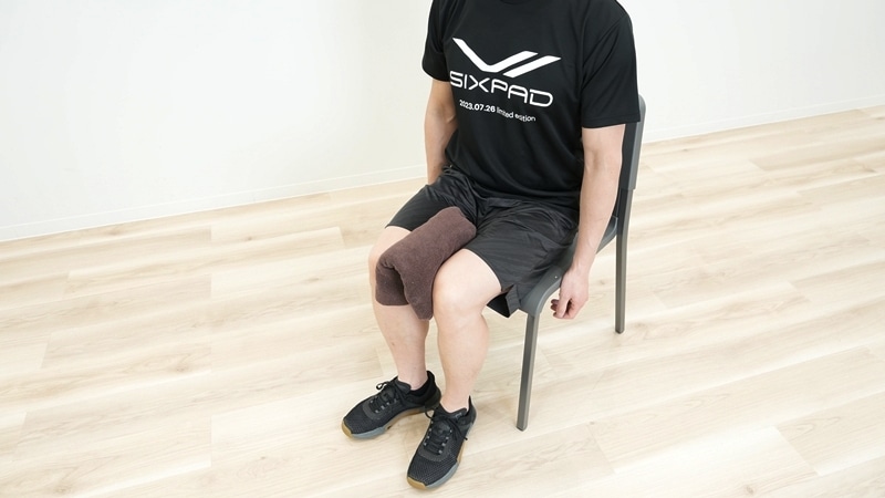 椅子に座り、足を腰幅程度に広げてボールやタオルなどを足の間に軽く挟む。